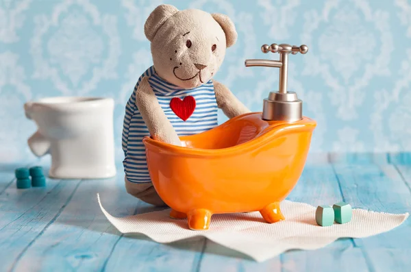Childrens soft toy teddy bear is bathed in orange bath doll house. Blue bathroom to . Playing with dolls in the family.  bathe in the .