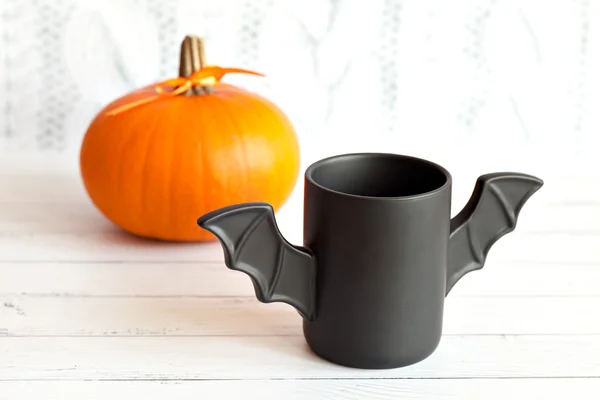 Cup of coffee like a bat in  red paper packaging for Halloween. White background. Toy  and pumpkin  concepts.
