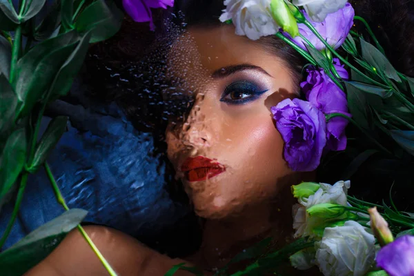 Fashion portrait of beautiful girl with bright make up among eustomas.