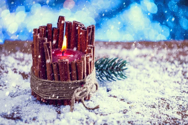 Snow Falling On Red Cinnamon Stick Christmas Candle Burning. Vintage Filter Applied.
