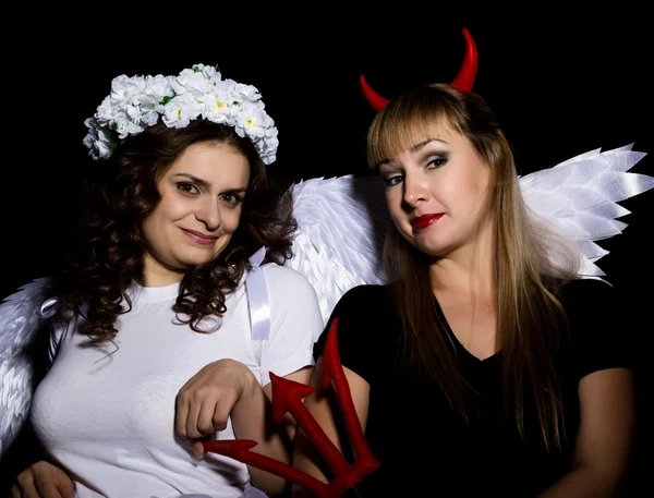 Portrait of angel and devil womans on a dark background