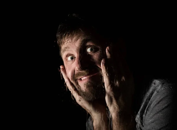Dark portrait of scary bearded man with smirk, expresses different emotions. Drops of water on a glass, hand and male face