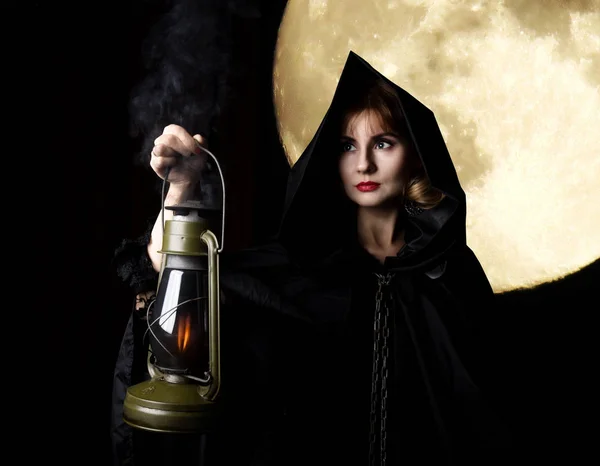 Mysterious young woman holding rope and old flashlight. on a dark moon background