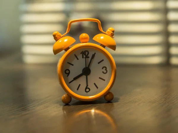 Old clock orange on the wooden table, select focus
