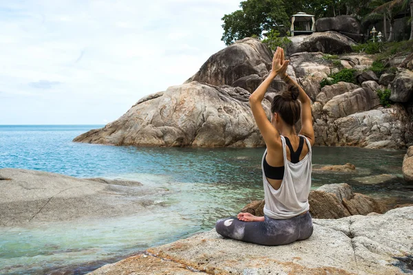 The girl meditating on stones by the sea, the Girl borrowing with yoga the island Samui, yoga in Thailand
