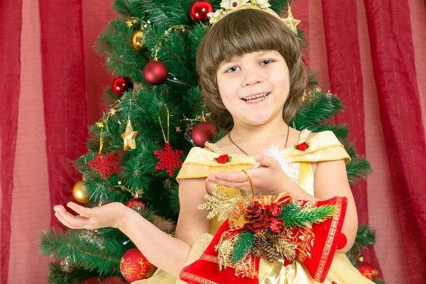 Happy little girl in a dress at Christmas. Happy little girl holding Christmas toy on the Christmas tree.