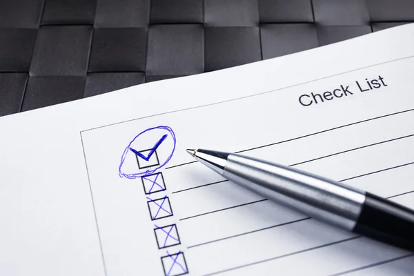 Checklist with a pen with check mark tick on black.