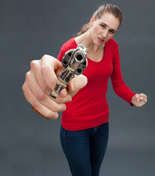Anxious beautiful young woman with gun expressing violence and intimidation