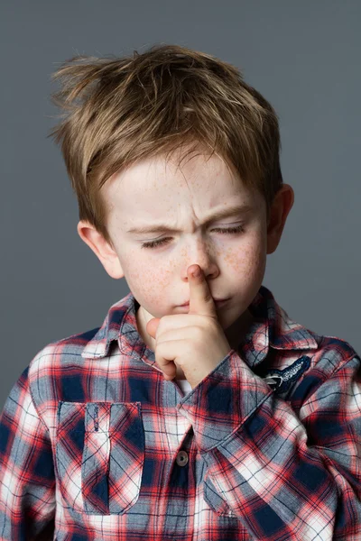 Young boy asking for silence, closing his eyes for concentration