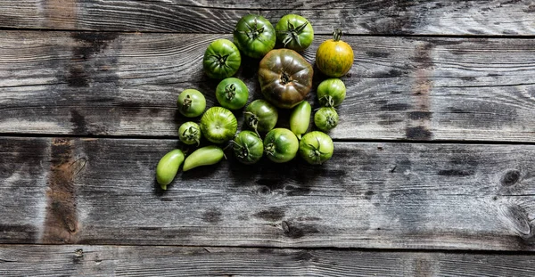 Various green tomatoes on simple wooden background for organic menu