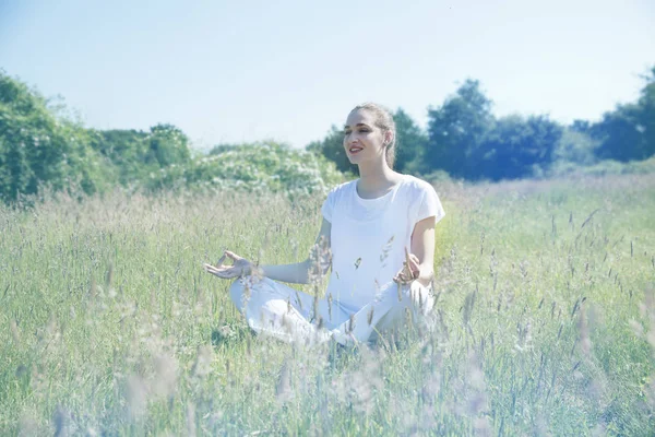 Smiling beautiful yoga girl meditating for openness in green environment