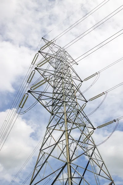 Electricity pylon silhouetted against blue sky wih cloud background. High voltage tower