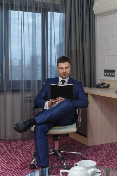 Young businessman sitting in a chair reading notepad