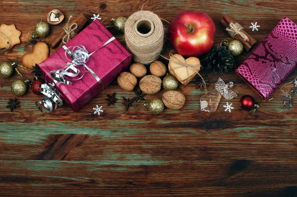 Christmas and New Year wallpaper (background). Gifts, ginger cookies, cones, Christmas balls, star anise, cinnamon, and other attributes of the Christmas holidays on the dark wooden surface. Spirit of Christmas