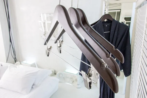Wooden cloth hangers on clothes rail and bathrobe
