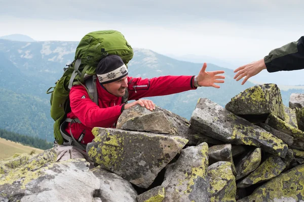 Hand helping hiker to climb the mountain