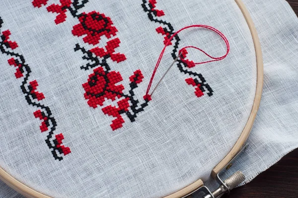 Traditional folk cross stitch floral pattern in a wooden hoop