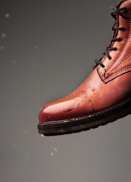 Leather boots waterproof protected brown color with water droplets. Shoes wax protect shoes from water