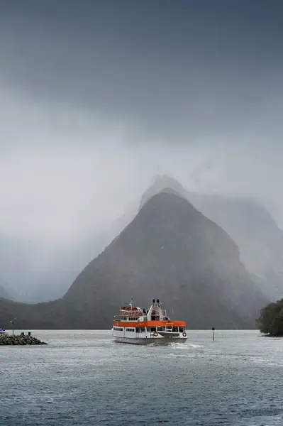 Milford Sound, New Zealand - February 2016: Tourist boat cruises in the fjord of Milford Sound, South island of New Zealand, with Mitre Peak seen in background