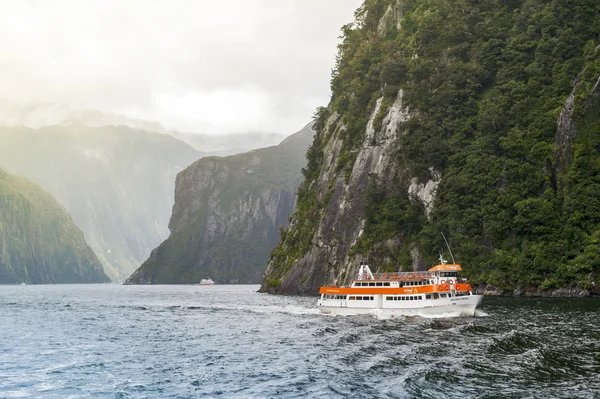 Milford Sound, New Zealand - February 2016: Tourist boat cruises in the fjord of Milford Sound, South island of New Zealand