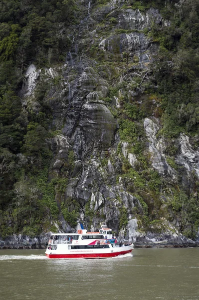 Milford Sound, New Zealand - February 2016: Tourist boat cruises in the fjord of Milford Sound, South island of New Zealand