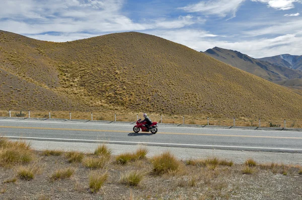 Otago, New Zealand - February 2016: Motorbike riding pass scenic lookout of Lindis Pass on State Highway 8 (Tarras - Omarama - Lindis Pass Road), lies between the valleys of the Lindis and Ahuriri Rivers, south island of New Zealand.