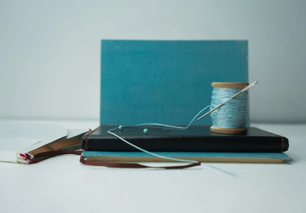 Still life. notebook, old spool of thread with a needle, pins, scissors. close-up.