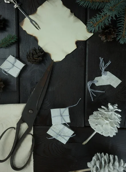 Gifts, paper, fir branch, old scissors and cones on a wooden table