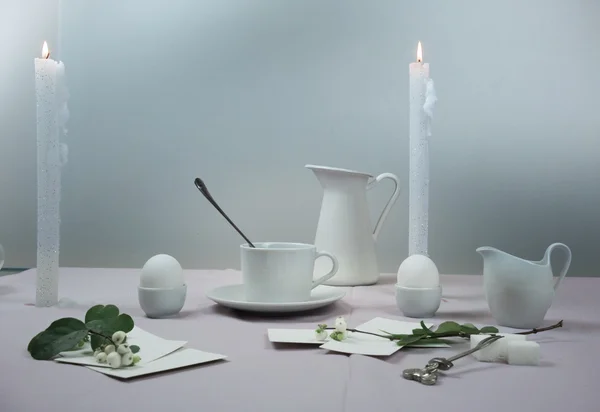 Still life. elegant table setting. tablecloth, candles, antique china - cup, saucer, eggs