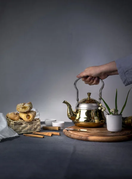 Still Life with a metal tea, cakes and vanilla on dark background. space for text.