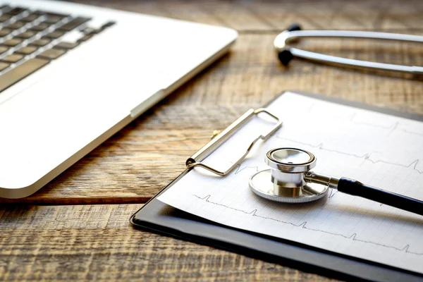 Doctor workplace with a stethoscope and laptop at wooden table