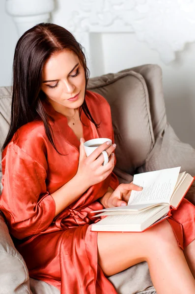 Young woman in the brown-haired sholkom dressing gown, sitting o