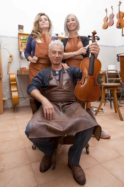 Group of mature violin maker in pose