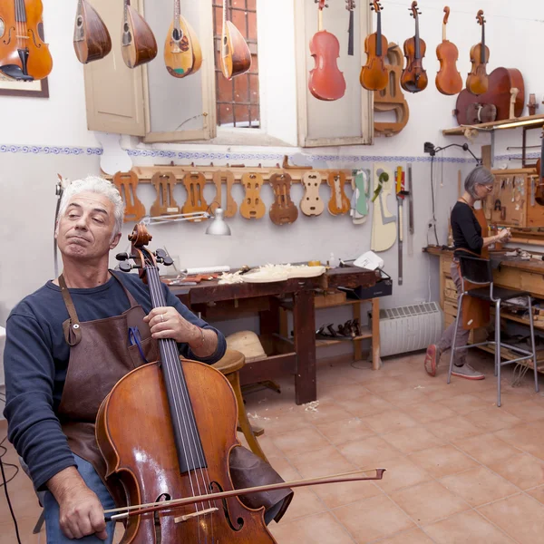 Portrait of mature violin maker while testing the violins in his