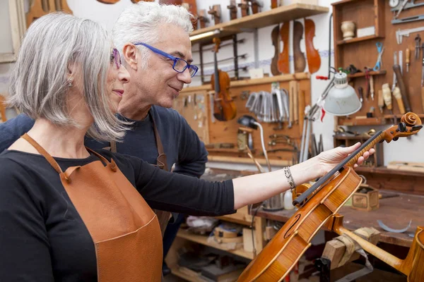 Group of mature violin maker in pose while testing the violins i
