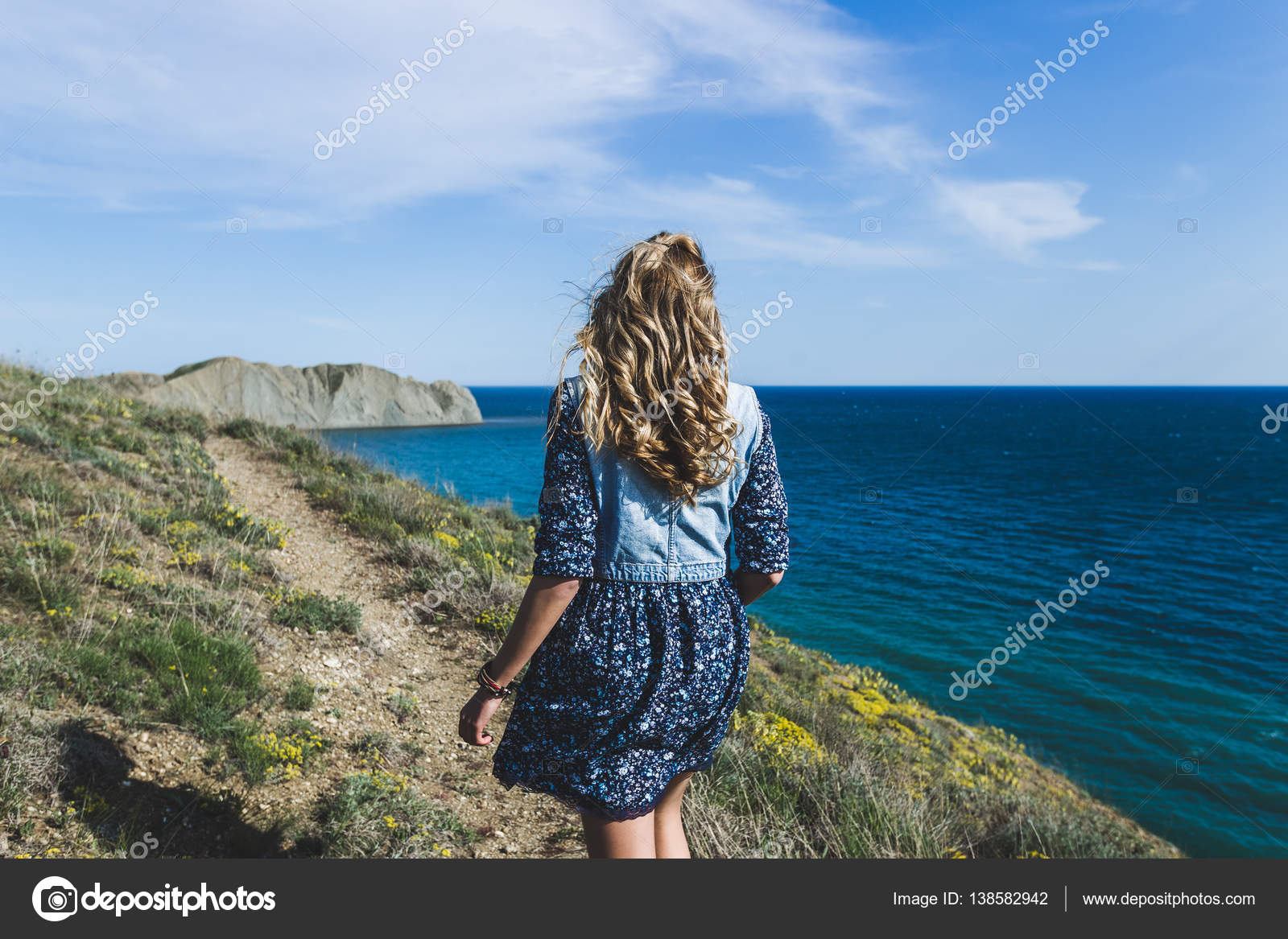 Девушка прогуливается по пляжу в платье приспуская его