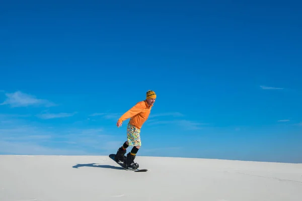 Man making a trick on snowboard on sand slope
