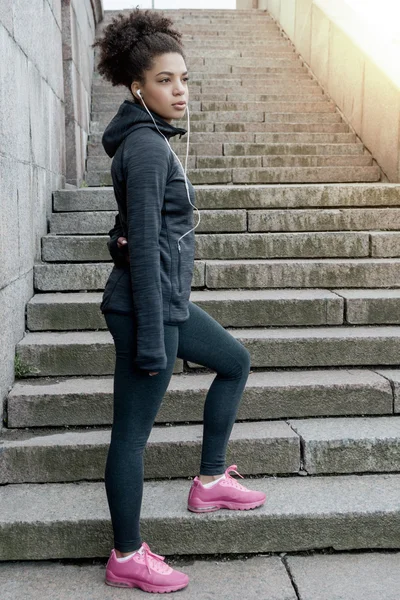 Side view of sporty woman standing at the base of stairs