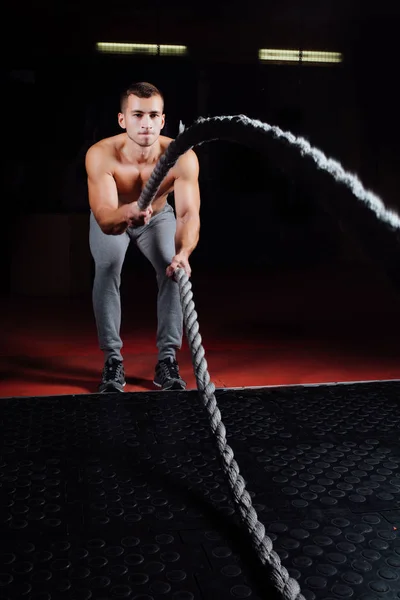 Men with battle rope in functional training fitness gym
