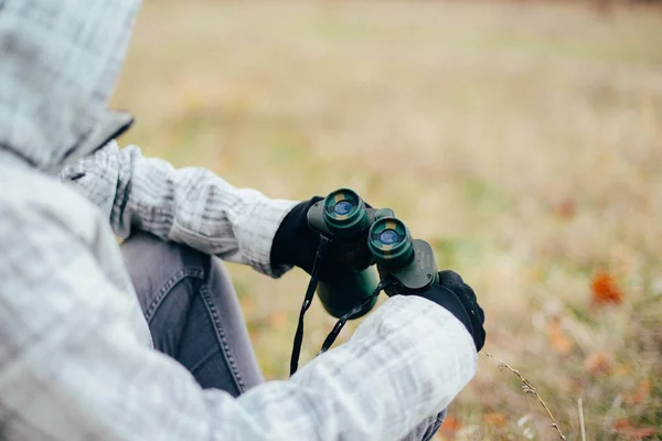 Young woman looking through binoculars on a autumn nature. Binoc