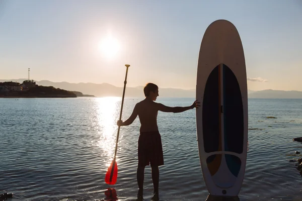 Silhouette of male with sup surf and paddle in hands at the ocean. Concept lifestyle, sport