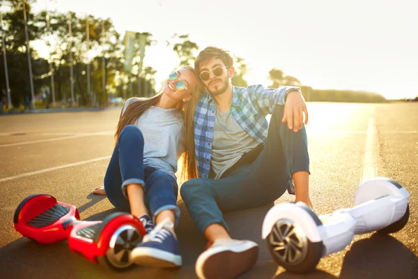 Young man and woman riding on the Hoverboard in the park. content technologies. a new movement