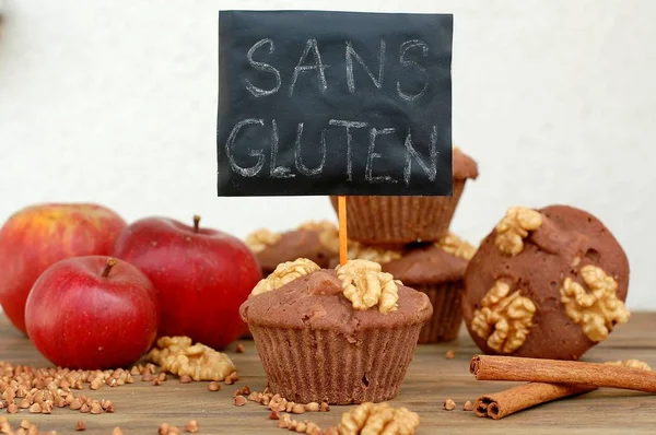 Gluten free muffins from buckwheat flour, apple, cinnamonand walnuts on brown wooden background with index card with text no gluten in french language