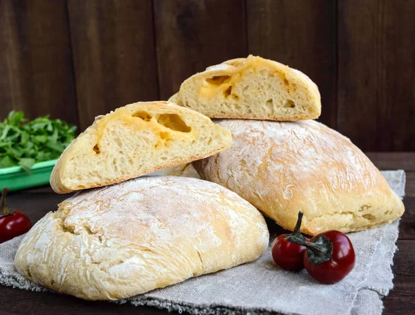 Ciabatta with cheese stuffing - freshly baked Italian white bread on a dark wooden background. For the preparation of sandwiches.