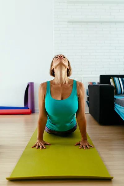 Athletic woman practicing yoga on a green mat indoor. vertical photo