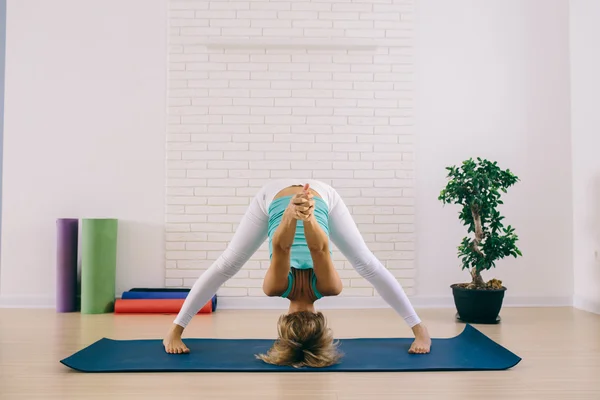 An attractive young woman doing a yoga pose head stand for balance and stretching
