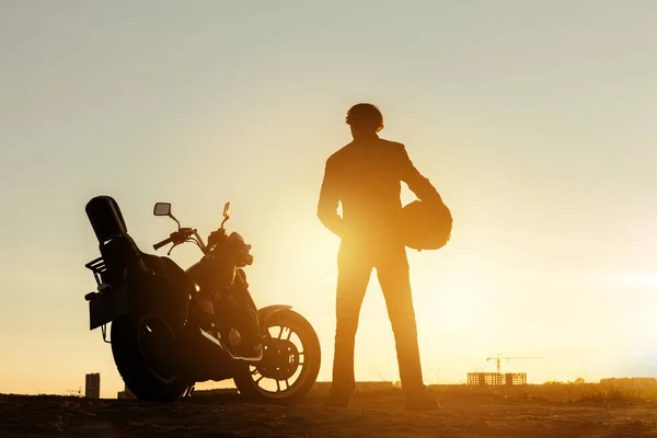 Biker with motorcycle at sunset time