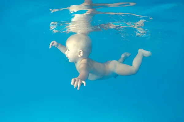 10 months infant boy learning to swim underwater in waterbaby class in the pool