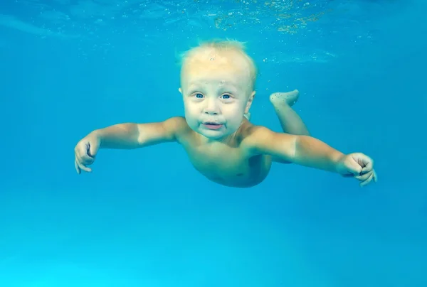 10 months infant boy learning to swim underwater in waterbaby class in the pool