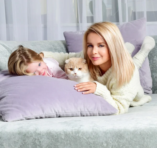 Mother and daughter at home with cat.